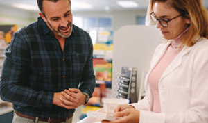 A man and woman discussing counselling checklists in a pharmacy store, surrounded by shelves of health products.