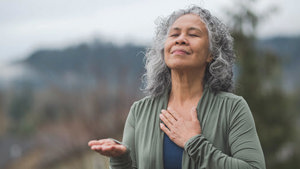 A mature woman clasps her hands in prayer